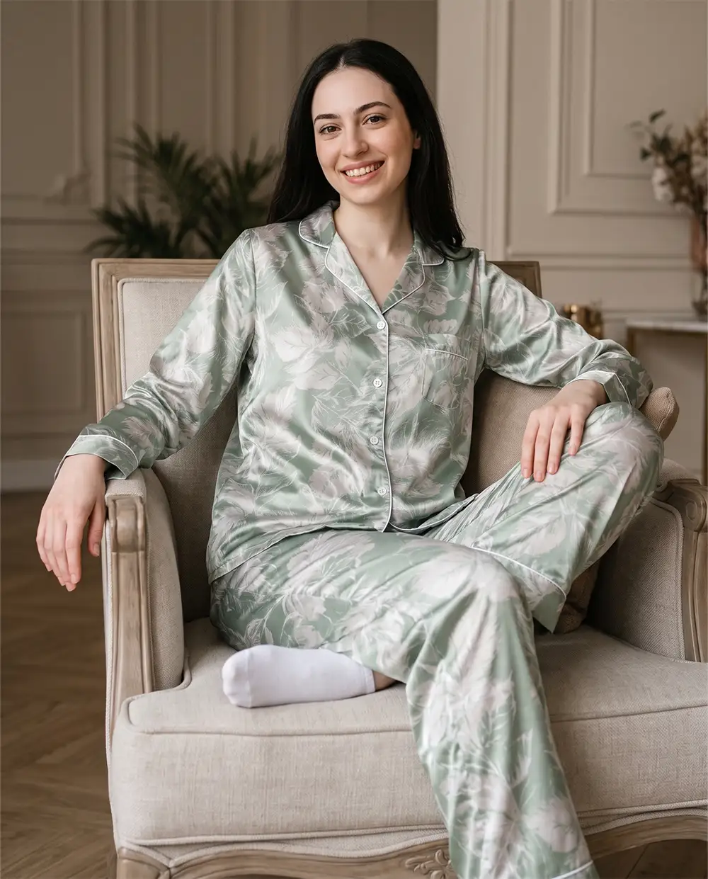 green-satin-sleepwear-lifestyle-model موديل ترتدي بيجامة ساتان حريرية بلون أخضر مريمي جالسة في المنزل